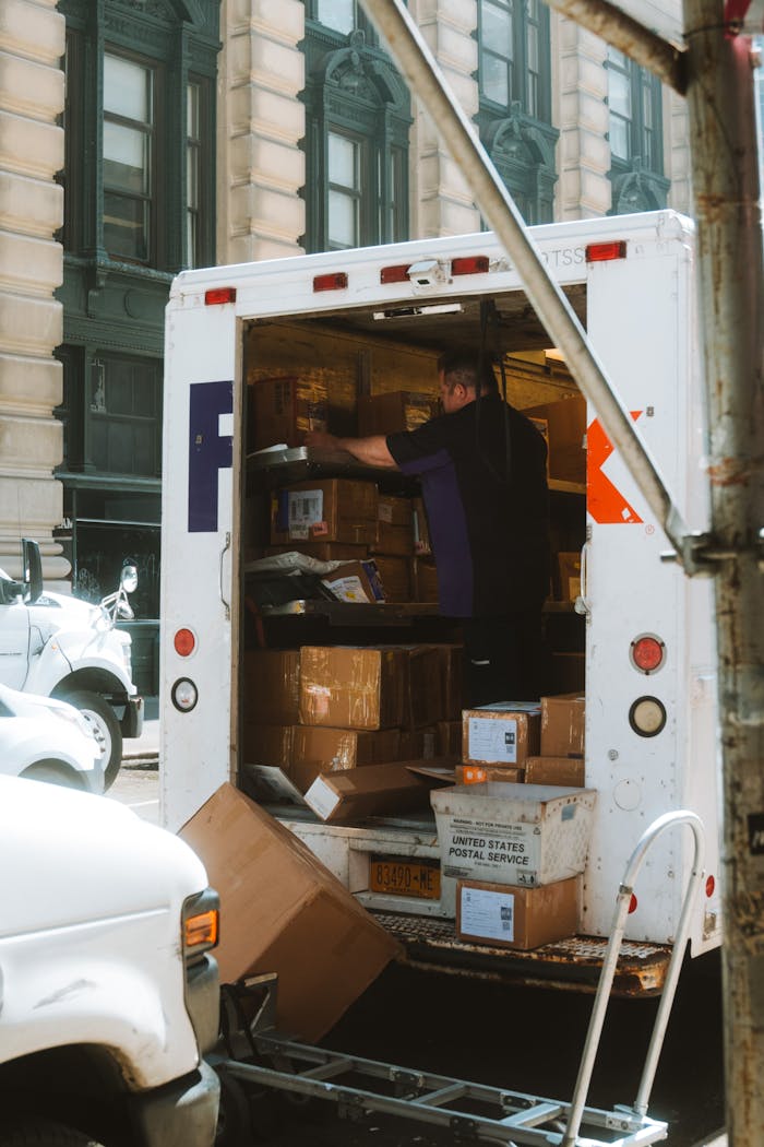 services-03 A delivery driver sorts packages in a truck on a busy urban street.
