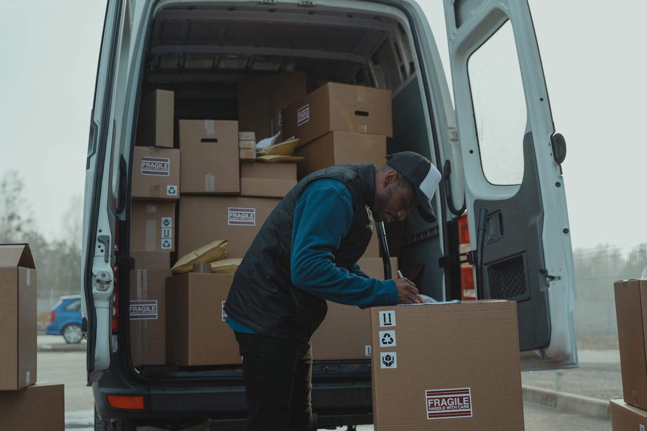 contact-img Delivery man sorting packages in van, organizing shipments for distribution.